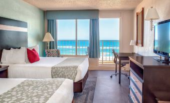 a hotel room with two beds , a desk , and a window offering a view of the ocean at Ramada Plaza by Wyndham Nags Head Oceanfront
