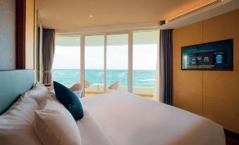 a large bed with white linens is in a room with a view of the ocean at Seashells Phu Quoc Hotel & Spa