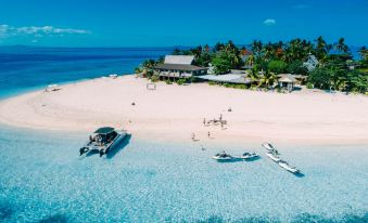 a beach scene with several boats docked on the sand , and a building in the background at Beachcomber Island Resort