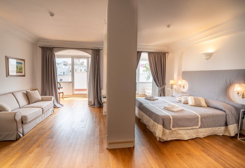 a large , well - lit room with wooden floors and white walls , featuring multiple beds and a couch at Covo dei Saraceni