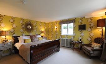 a large bed with a wooden headboard is in the center of a room with floral wallpaper at The White Hart