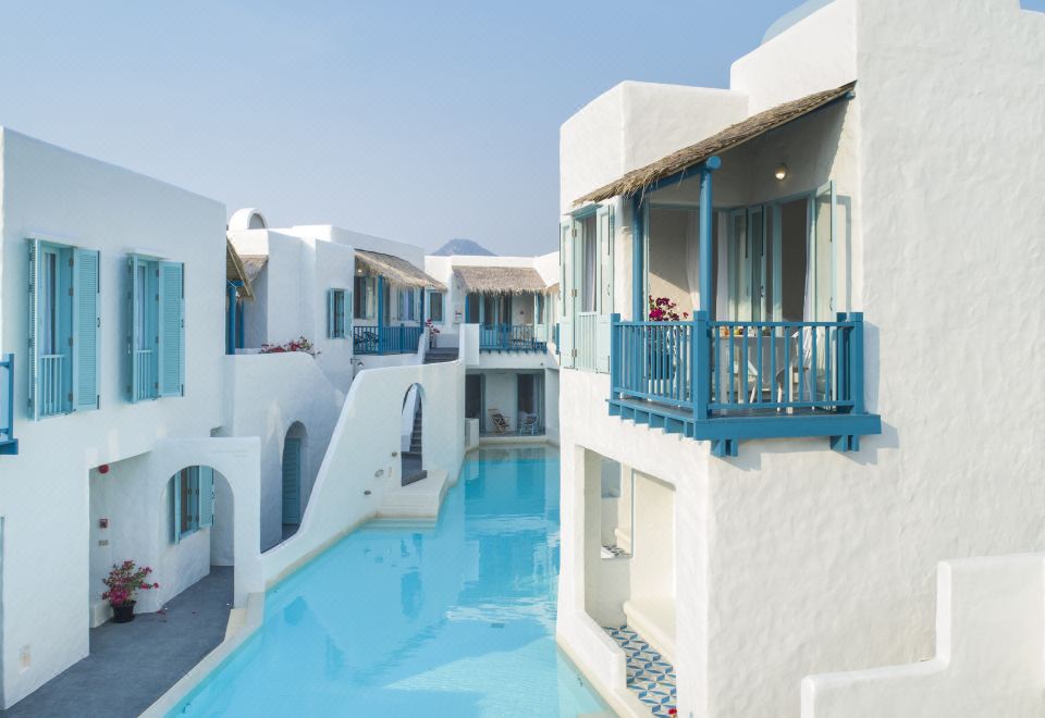 a group of white buildings with blue balconies and a swimming pool in front of them at Resort de Paskani