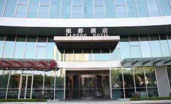 The front entrance of a hotel in an urban setting features large glass and steel doors at Yindu Hotel