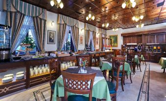 a restaurant with wooden tables and chairs , a bar , and several large windows covered by striped curtains at Green Garden Hotel