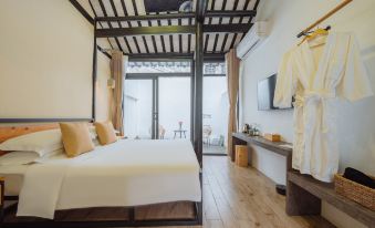 a modern bedroom with a white bed , wooden flooring , and a balcony offering views of the ocean at Floral Hotel · Mowan hotel (Tongli Ancient Town)