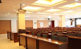 a large conference room with wooden tables and chairs arranged in rows , and a stage at the end of the room at Frontier Building