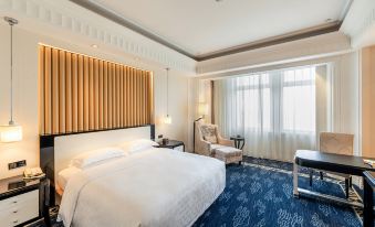 The bedroom is furnished with a bed, desk, and large windows at Inspirock Hotel