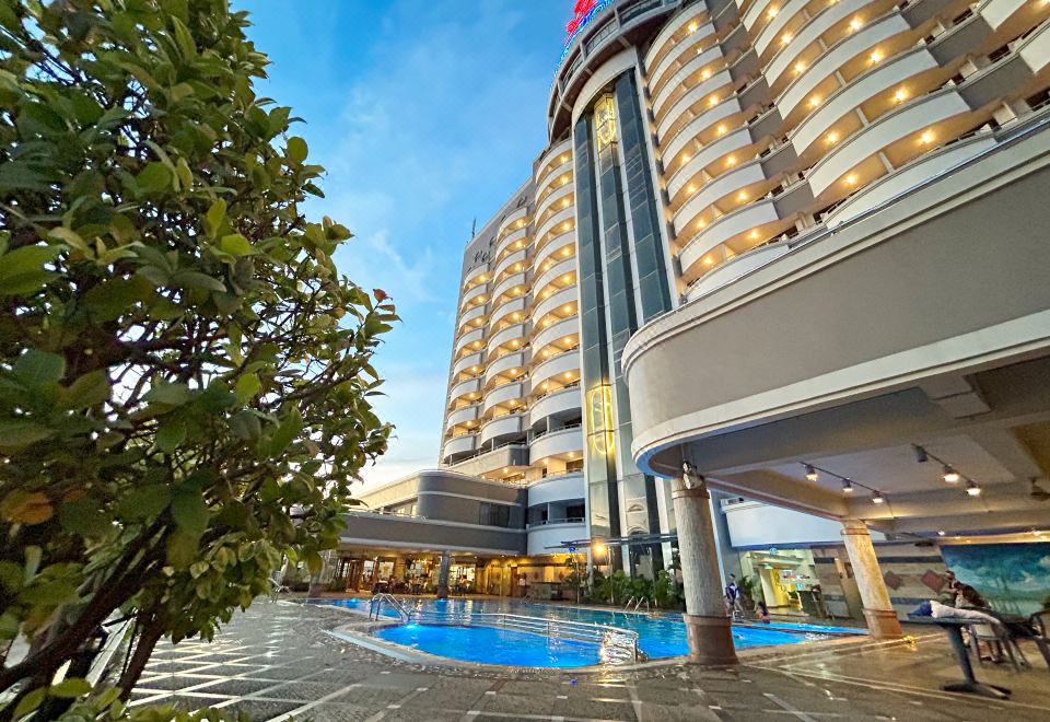 a large hotel with a pool in the courtyard , surrounded by trees and other buildings at Planet Holiday Hotel & Residence