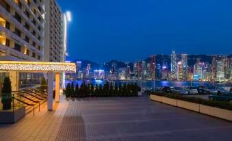 At the top floor level, there is a city at night with a lit-up skyline and water in front at Marco Polo Hongkong Hotel
