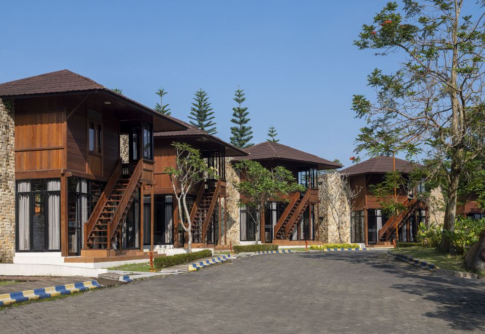 a row of wooden houses with stone exteriors and large windows , surrounded by trees and clear skies at Jsi Resort