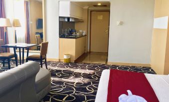 a hotel room with a kitchenette and dining area , along with a bed and chair at Planet Holiday Hotel & Residence