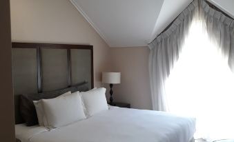 a large bed with white linens is situated in a room with a sloped ceiling and a window at Hotel Venezia