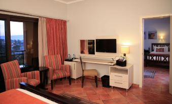 a hotel room with a bed , chair , desk , and tv . also a chair in the room at Haile Resort Hawassa