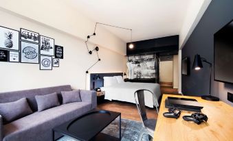 The living room is furnished with a sofa, bed, and table arranged in close proximity to each other at Pentahotel Hong Kong, Tuen Mun