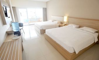 a hotel room with two beds , a desk , and a sliding glass door leading to a balcony at Laut Biru Resort Hotel