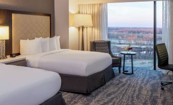 a hotel room with two twin beds , a nightstand , and a view of the city at Hilton Shreveport