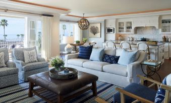 a modern living room with white and blue furniture , a brown ottoman , and a dining table at Montage Laguna Beach