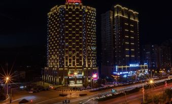 A city at night with buildings illuminated in blue and white hues on both sides at Hampton by Hilton Ji'an