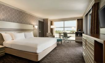 a modern hotel room with a large window offering a view of the city , white bed , and comfortable seating area at Hilton Melbourne, FL