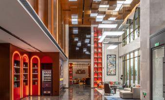 The modern building features a spacious lobby and entrance adorned with large floor-to-ceiling windows on both sides at Hampton by Hilton Qingdao West Coast