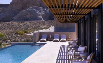 a large pool surrounded by lounge chairs , with a view of mountains in the background at Amangiri
