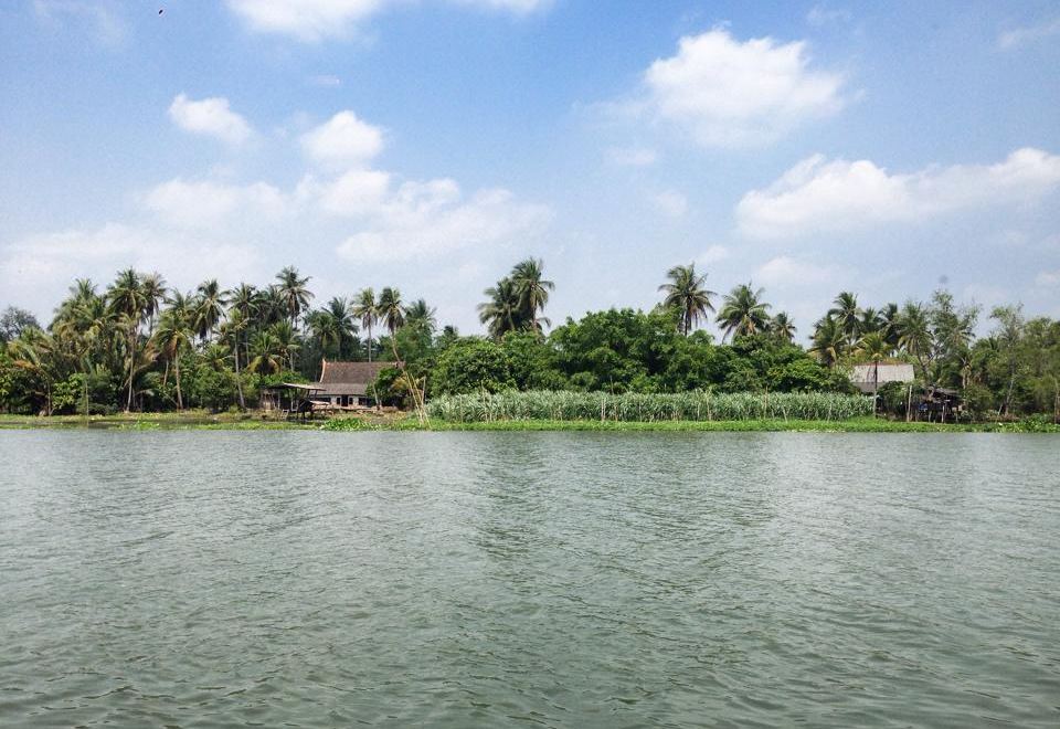 a body of water surrounded by lush green vegetation , with palm trees and buildings in the background at Parn Dhevi Riverside Resort & Spa