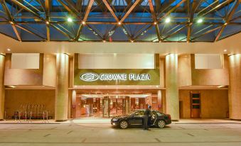 At night, there is a large building with an entrance where cars are parked outside the front door at Crowne Plaza Guangzhou City Centre