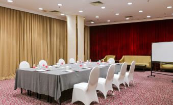 A spacious event room is arranged with long tables and chairs facing the front at Ramada Plaza by Wyndham Shanghai Pudong Airport