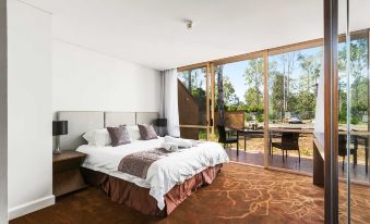 a large bedroom with a king - sized bed and a sliding glass door leading to a balcony overlooking trees at The Kooralbyn Valley