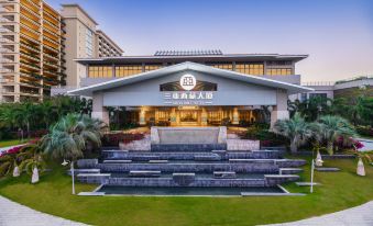a large building with a fountain in front of it , surrounded by grass and trees at Sanya Xizang Hotel