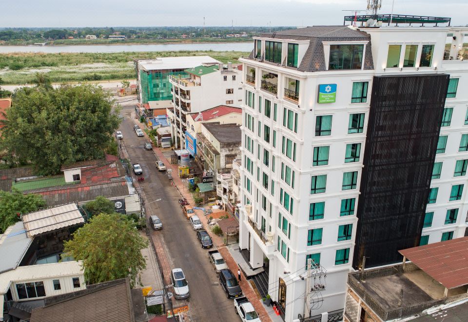 an aerial view of a city street with a tall white building and several cars parked on the side at SureStay Hotel by Best Western Vientiane