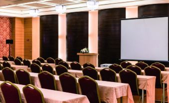 a conference room with rows of chairs arranged in a semicircle , and a projector screen mounted on the wall at Fish Hotel -Taitung