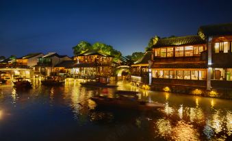 A city at night with boats on the water and buildings lining both sides at WUZHEN REZEN SELECT HOTEL