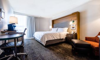 a modern hotel room with a large bed , desk , and chair , as well as a window offering a view of the city at Holiday Inn Grand Haven-Spring Lake