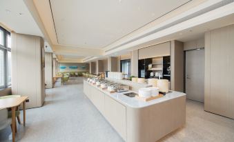 has a spacious layout and is equipped with tables and chairs, situated adjacent to a fully visible open kitchen at JI Hotel (Shenzhen Huaqiangbei Huaqiang Road Subway Station)