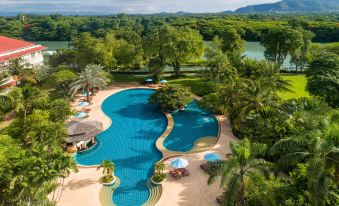 a beautiful resort with multiple swimming pools , umbrellas , and lush greenery surrounding a river surrounded by mountains at Dheva Mantra Resort