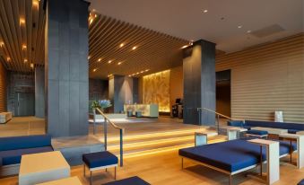 a modern hotel lobby with a wooden staircase leading to the second floor , surrounded by chairs and couches at Hotel Clad