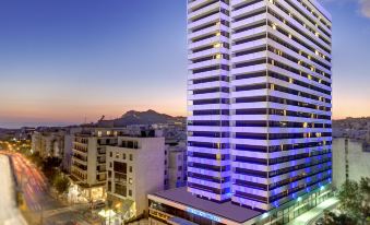 a tall , modern building with blue lights is situated next to a street and cityscape at President Hotel