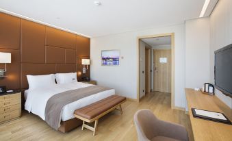 a modern bedroom with a large bed , wooden furniture , and a chair near the door at DoubleTree by Hilton Istanbul-Avcilar