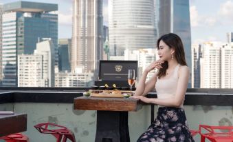 A woman sits at a table on her balcony, overlooking the city and other buildings at Hotel Indigo Shanghai on The Bund