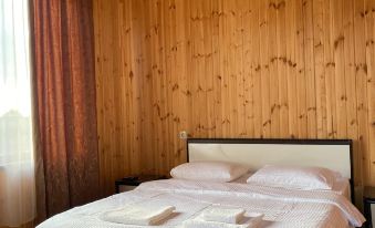 a bedroom with wooden walls and a bed covered in white sheets , both of which have towels folded on them at ELION