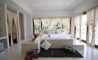 a white bedroom with a large bed and a bench in front of the bed at Proud Phu Fah Hip & Green Resort