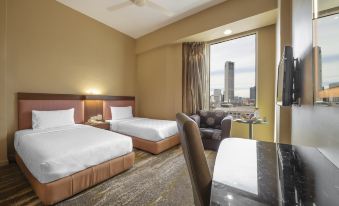 a hotel room with two beds , a desk , and a chair , all arranged in a modern setting at Cititel Penang