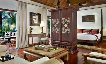 a living room with a wooden cabinet and a coffee table , surrounded by various items at Anantara Hua Hin Resort
