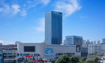 There is a large building with many windows and an office tower in the middle on one side at Fuzhou Le'an New Century Mingting Hotel
