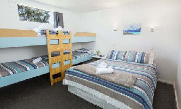 a bedroom with a bed and bunk beds , featuring striped bedding and a window view at North South Holiday Park