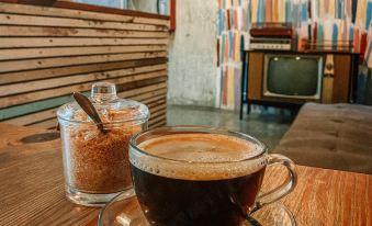 a cup of coffee with a spoon and a bowl of sugar on the side at The Bricks Hotel