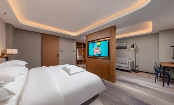 A modern bedroom is equipped with a large bed and a flat-screen TV mounted on the wall above it at Guangzhou Yuexiu International Convention Center Park Hotel