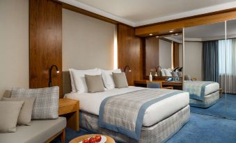 a hotel room with a king - sized bed , two chairs , and a dining table in the corner at Radisson Blu M'Bamou Palace Hotel, Brazzaville