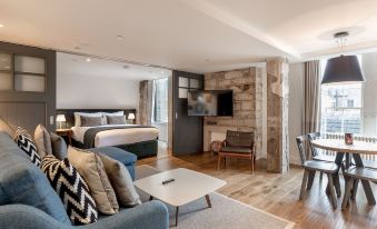 a modern living room and bedroom area with a couch , coffee table , television , and large window at Old Town Chambers, Autograph Collection
